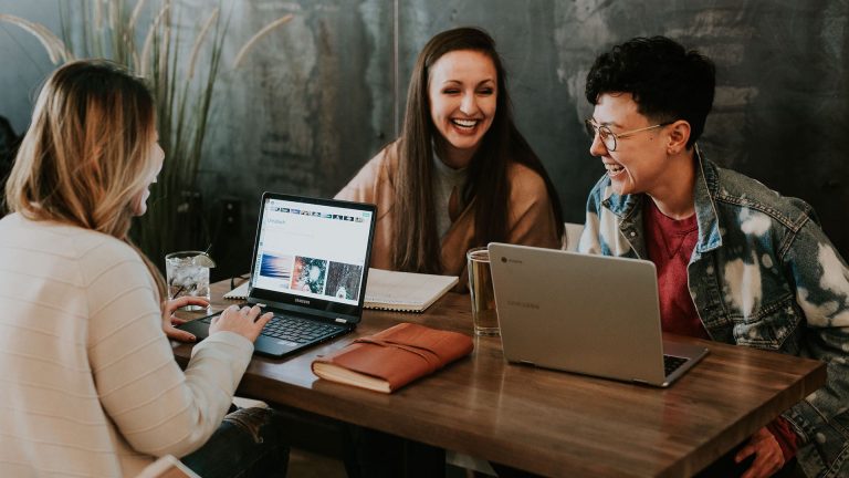 Business people laughing at a table with their laptops