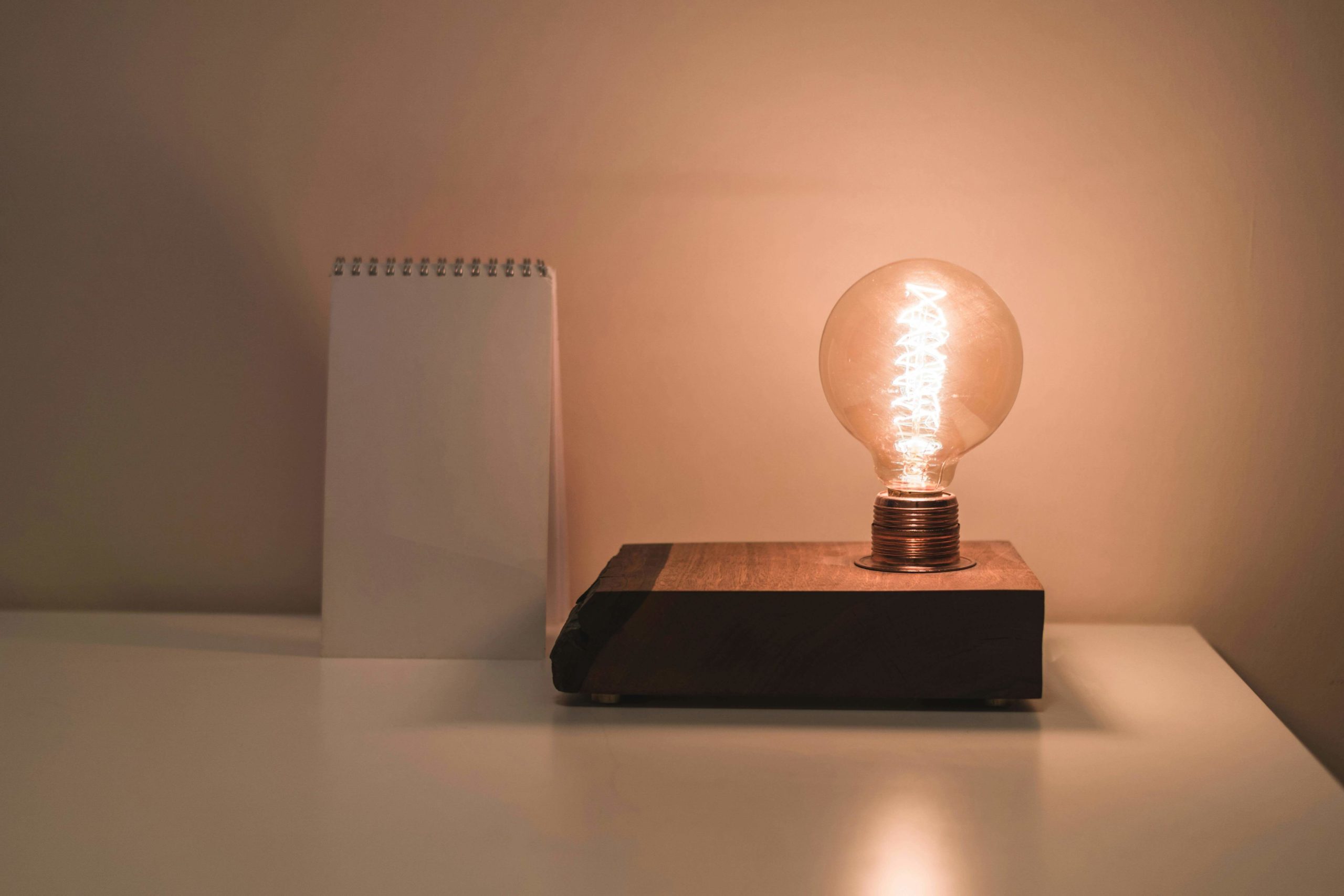 bright light bulb and note pad on a desk