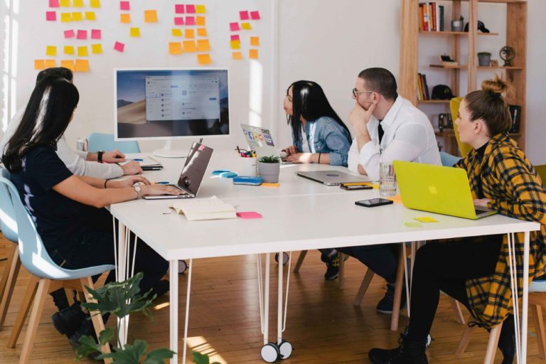 Team members reviewing marketing items in an office on a screen and board