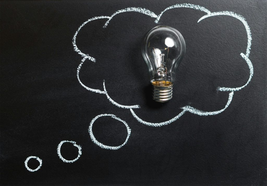 idea lightbulb on a black chalkboard with chalk thought bubble