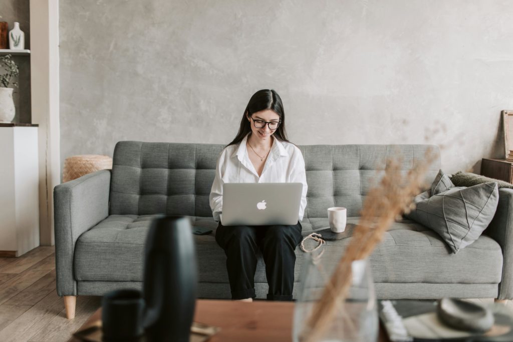 woman sitting on a couch looking at her emails on laptop